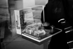 A black and white photo of a boxed camera kit labeled "Photo Lab Outfit" near a guitar. The boutique photo captures various film development items such as film canisters and cameras, evoking memories of Kanab, Utah. The background is out of focus, giving the image a nostalgic feel.