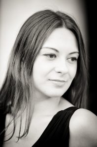 A Noir et Blanc portrait of Anaïs, a woman with long, straight hair, looking softly to the side in a calm expression. She is wearing a sleeveless, dark-colored top, evoking the timeless elegance of Jardin du Palais-Royal.