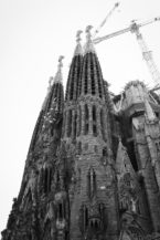 Black and white photo of Gaudi’s iconic Sagrada Familia basilica in Barcelona, showcasing its ornate, towering spires and construction cranes in the background.