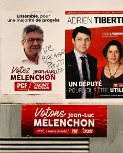 A wall in Paris boasts political posters promoting Jean-Luc Mélenchon and Adrien Tiberti for the PCF (Parti Communiste Français). Amidst the campaign, one poster defaced with "Votez Bachar Poutin" obscures Mélenchon's face. Below it, another red poster urges support for Mélenchon.