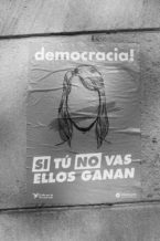 Black and white poster on a wall with the word "democracia!" at the top and a faceless silhouette of a woman. Below the image, the text reads "SI TÚ NO VAS ELLOS GANAN." The posters highlight key moments like Référendum de 2017 in Barcelone. Logos of Crida per la Democràcia and Òmnium are at the bottom