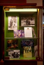 A glass display case with vintage black-and-white and colour photos of people socialising at Parisian cafés in the 1970s, plus an informational card titled "Les Cafés de Paris.