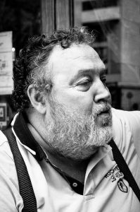Black and white profile portrait of Jean Benoit Roubinet, a middle-aged man with a curly beard wearing a collared shirt and braces.