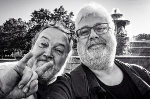 Two bearded men taking a selfie in front of a fountain at the Salon de la photo.