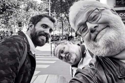 Three men posing for a close-up selfie on a Paris city street during the Salon de la photo.