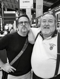 Two middle-aged men, including Jean Benoit Roubinet, posing for a photo with one man resting his arm on the other’s shoulder at the Salon de la Photo 2026.